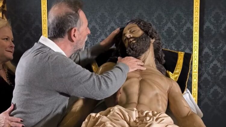 Personas ciegas palpan al Cristo Yacente de la Hermandad de la Vera-Cruz en Utrera