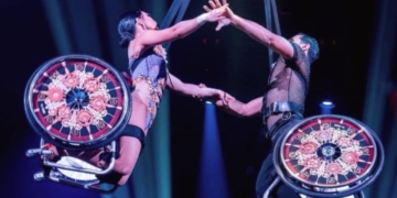 Dúo de acróbatas en silla de ruedas realizando una figura aérea