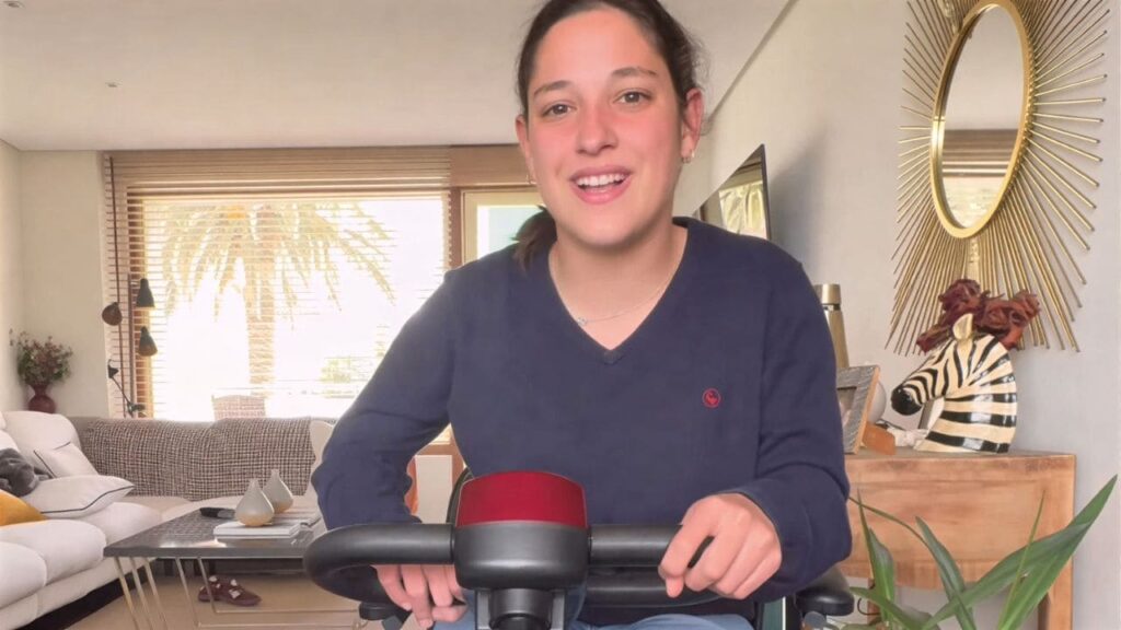 Una joven con movilidad, sobre la silla de ruedas eléctrica de la Seguridad Social y 'su' Scooter