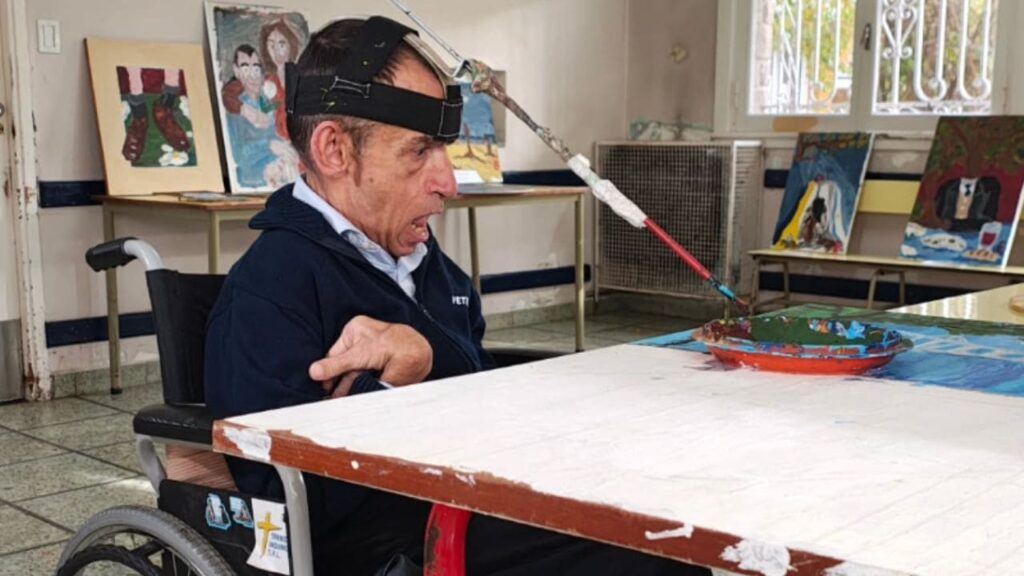 Eduardo Ríess, un hombre de 62 años con parálisis cerebral que pinta cuadros con un pincel atado a su cabeza